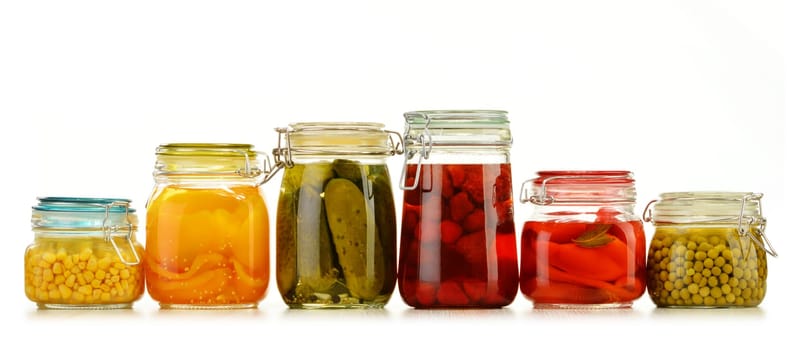 Jars with pickled vegetables and fruity compotes isolated on white background. Preserved food