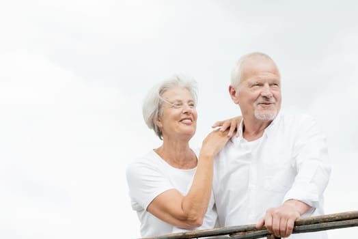 Active and happy senior couple in front of a bright sky
