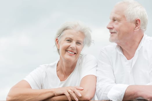 Active and happy senior couple in front of a bright sky