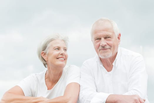 Active and happy senior couple in front of a bright sky