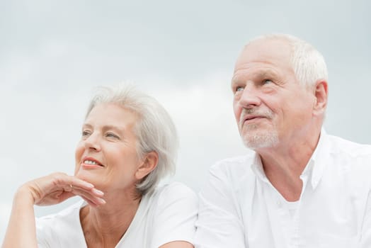 Active and happy senior couple in front of a bright sky