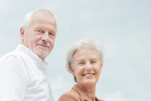 Active and happy senior couple in front of a bright sky