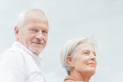 Active and happy senior couple in front of a bright sky