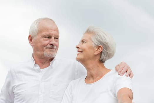 Active and happy senior couple in front of a bright sky