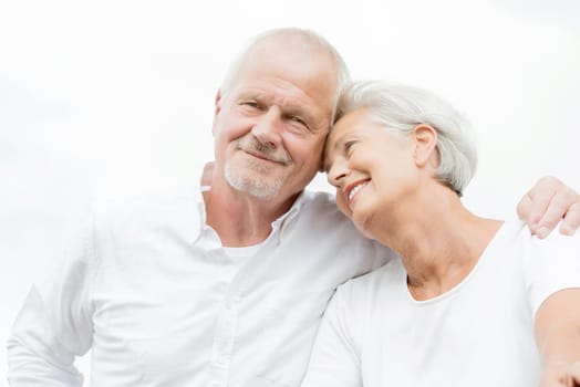 Active and happy senior couple in front of a bright sky