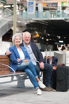 Two laughing seniors on a bench in the train station