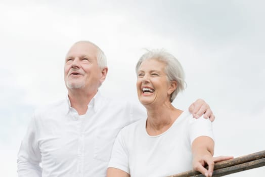 Active and happy senior couple in front of a bright sky