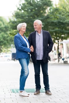 Full body shot of a senior couple against an urban background