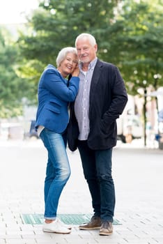 Full body shot of a senior couple against an urban background