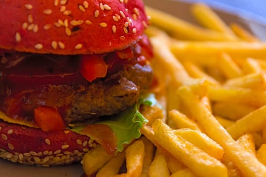 Fresh, juicy burger with tangy Mexican Tabasco sauce and French fries closeup. Fast food background.