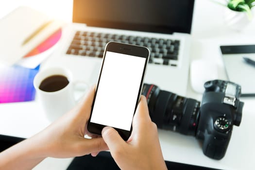 creative photogeapher holding phone white screen on workspace table, phone blank screen for adjustment mobile app