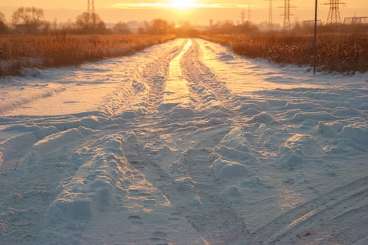 A snowy road in the suburbs during sunset