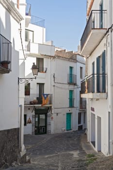 Narrow street with white houses in historical center of Cadaques, Spain