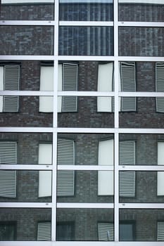The abstract reflection of windows with shutters in mirrored windows.