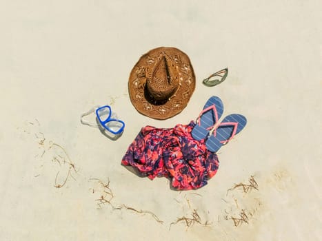 The straw hat, mask, sun glasses and dress on a tropical beach
