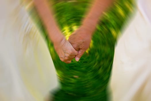 Concept shoot of friendship and love of old man and woman: two hands over green grass
