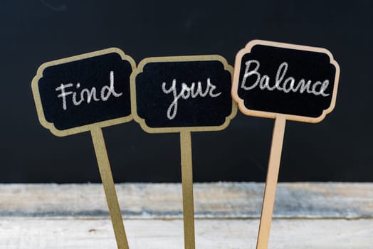 Motivational message Find Your Balance written with chalk on wooden mini blackboard labels, defocused chalkboard and wood table in background