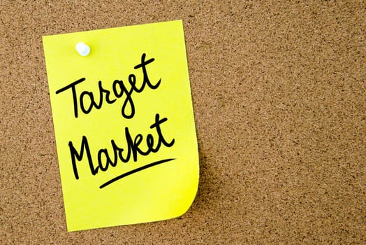 Target Market text written on yellow paper note pinned on cork board with white thumbtack. Business concept image with copy space available