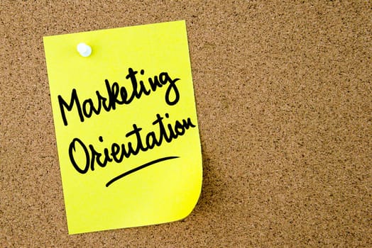 Marketing Orientation text written on yellow paper note pinned on cork board with white thumbtack. Business concept image with copy space available
