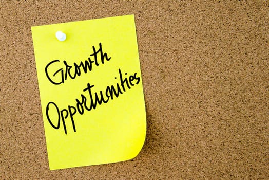 Growth Opportunities text written on yellow paper note pinned on cork board with white thumbtack. Business concept image with copy space available