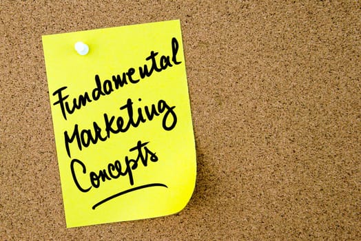Fundamental Marketing Concepts text written on yellow paper note pinned on cork board with white thumbtack. Business concept image with copy space available