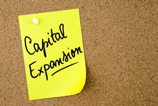 Capital Expansion text written on yellow paper note pinned on cork board with white thumbtack. Business concept image with copy space available