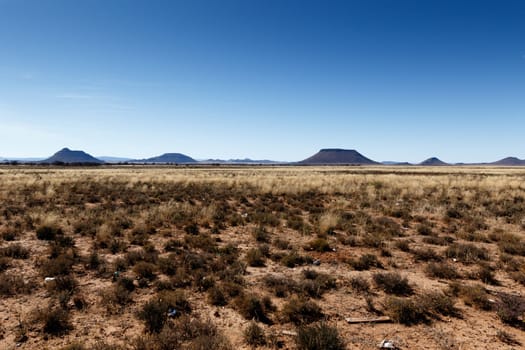 Cradock with yellow fields and  mountains with blue sky in South Africa.