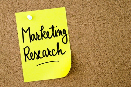 Marketing Research text written on yellow paper note pinned on cork board with white thumbtack. Business concept image with copy space available