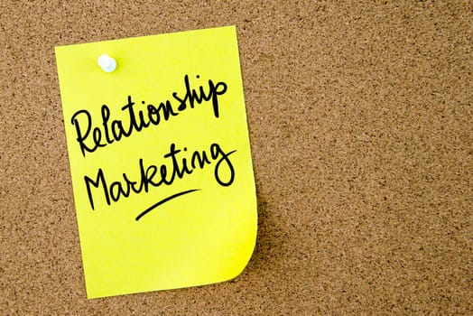 Relationship Marketing text written on yellow paper note pinned on cork board with white thumbtack. Business concept image with copy space available