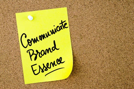 Communicate Brand Essence text written on yellow paper note pinned on cork board with white thumbtack. Business concept image with copy space available