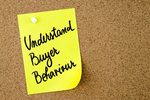 Understand Buyer Behaviour text written on yellow paper note pinned on cork board with white thumbtack. Business concept image with copy space available