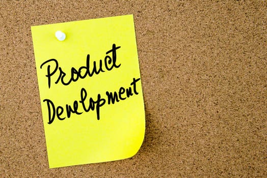 Product Development text written on yellow paper note pinned on cork board with white thumbtack. Business concept image with copy space available