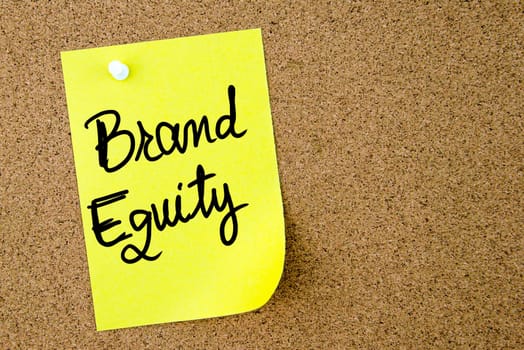 Brand Equity text written on yellow paper note pinned on cork board with white thumbtack. Business concept image with copy space available