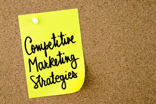 Competitive Marketing Strategies text written on yellow paper note pinned on cork board with white thumbtack. Business concept image with copy space available
