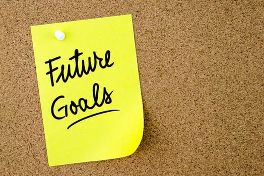Future Goals text written on yellow paper note pinned on cork board with white thumbtack. Business concept image with copy space available