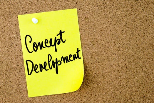 Concept Development text written on yellow paper note pinned on cork board with white thumbtack. Business concept image with copy space available