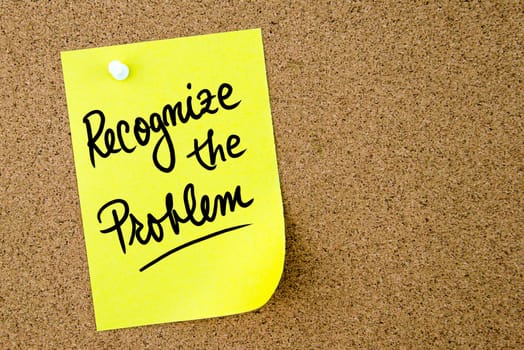 Recognize the problem text written on yellow paper note pinned on cork board with white thumbtack. Business concept image with copy space available