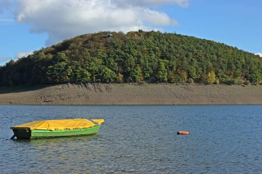 Green-yellow fishing boat in the empty Edersee on the treetop path