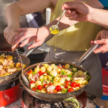 Cheff cooking traditional Mediterranean octopus with potatoes and vegetable on street stall on international street food festival of Odprta kuhna, Open kitchen event, in Ljubljana, Slovenia.