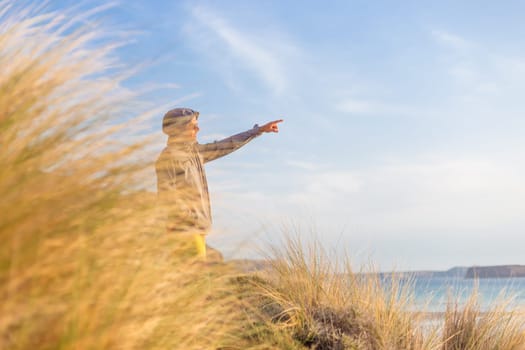 Sporty active man pointing hand on horizon, enjoying beauty of nature, freedom and life at beautiful landscape. Active lifestyle outdoors.