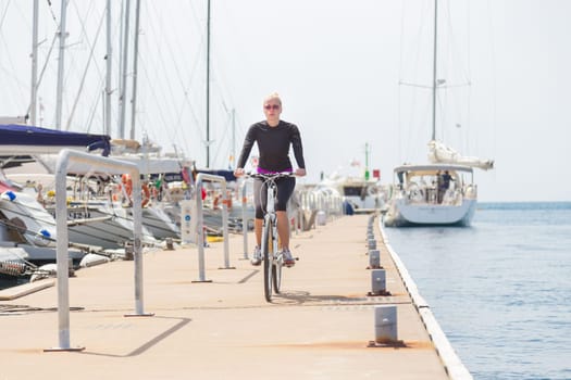 Young active woman cycling on pier in Rovinj marina, Istria, Croatia