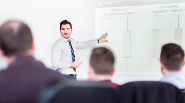Business man making a presentation at office. Business executive delivering a presentation to his colleagues during meeting or in-house business training, explaining business plans to his employees.