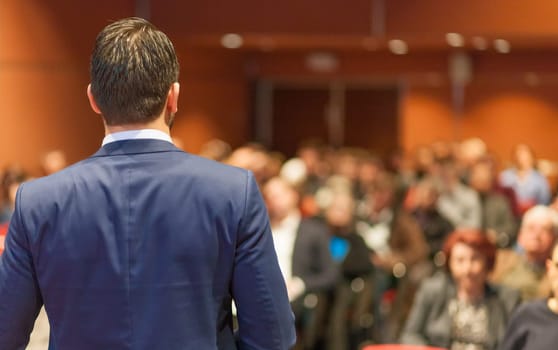 Speaker giving a talk on corporate Business Conference. Audience at the conference hall. Business and Entrepreneurship event.