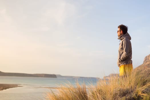 Sporty active man looking in distance, enjoying beauty of nature, freedom and life at beautiful landscape. Active lifestyle outdoors.