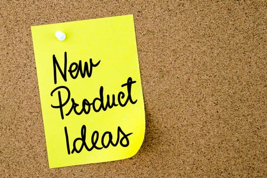 New Product Ideas text written on yellow paper note pinned on cork board with white thumbtack. Business concept image with copy space available