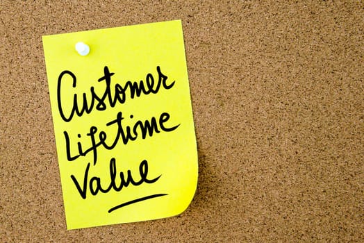 Customer Lifetime Value text written on yellow paper note pinned on cork board with white thumbtack. Business concept image with copy space available