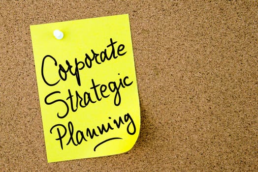 Corporate Strategic Planning text written on yellow paper note pinned on cork board with white thumbtack. Business concept image with copy space available
