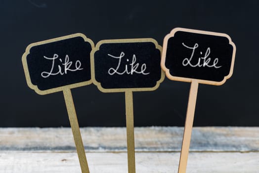 Motivational message Like, Like, Like written with chalk on wooden mini blackboard labels, defocused chalkboard and wood table in background