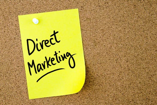 Direct Marketing text written on yellow paper note pinned on cork board with white thumbtack. Business concept image with copy space available