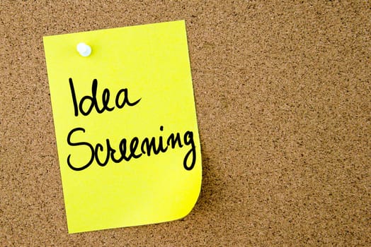 Idea Screening text written on yellow paper note pinned on cork board with white thumbtack. Business concept image with copy space available